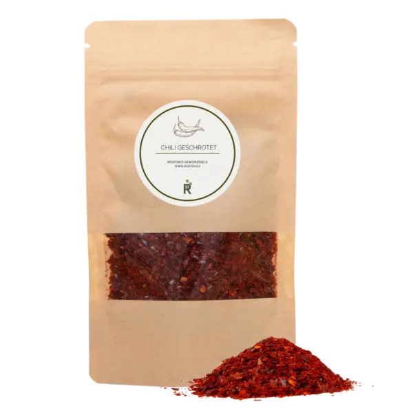Das Bild zeigt einen Haufen Chili geschrotet vor einer Verpackung.