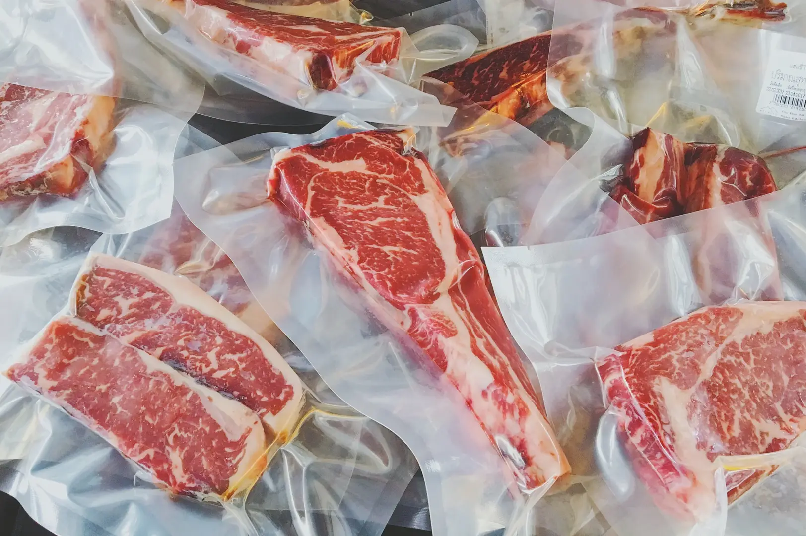 Auf dem Bild sieht man einen Haufen verschiedener roher Fleischsorten in Dry Aging Beutel eingeschweißt.